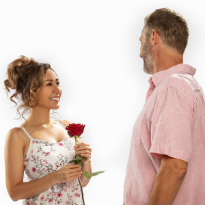 Eine Frau lächelt einen Mann an und hält eine rote Rose, symbolisierend Wertschätzung und liebevolle Begegnung im Kontext von Tantra Massage und Beziehungen.