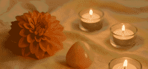 Warme Atmosphäre mit orangefarbener Blüte, spirituellem Stein und Kerzenlicht. Symbolisiert achtsame Berührung und Tantra Massage lernen.