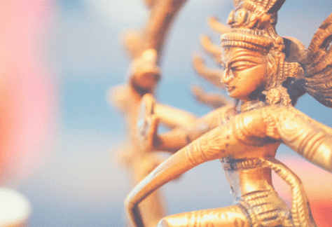 Eine detaillierte goldene Shiva Nataraja Statue, die den kosmischen Tänzer darstellt, symbolisierend Schöpfung, Erhaltung und Zerstörung sowie die dynamische Energie und Transformation in der Tantra Massage und spirituellen Praxis.