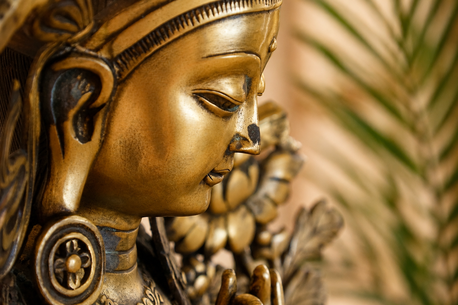 Goldene Statue einer hinduistischen Göttin mit sanft gesenktem Blick und gefalteten Händen als Symbol für Achtsamkeit und Spiritualität.
